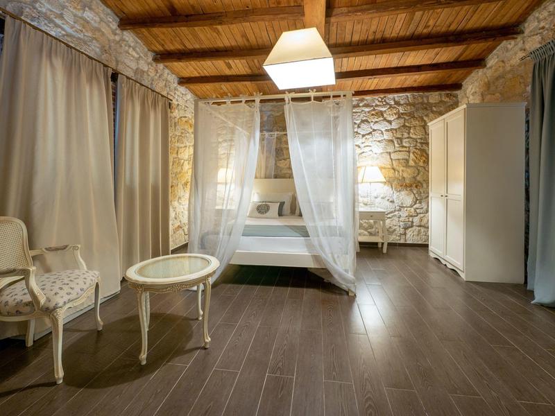 Cozy hotel room with wooden beam ceiling, elegant curtains, and antique furniture.