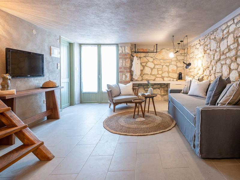Living room with stone wall, gray sofa, round rug, and large window in modern design.