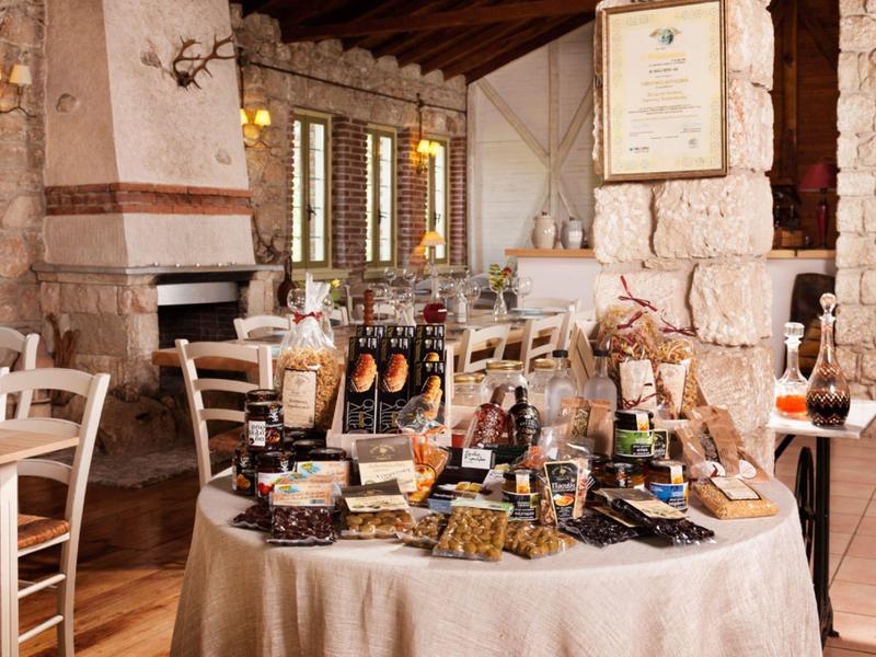 Rustic hotel lounge with round table full of local products and wooden chairs.