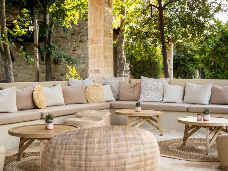 Cozy outdoor lounge with cushioned seating, wooden tables, and natural plants