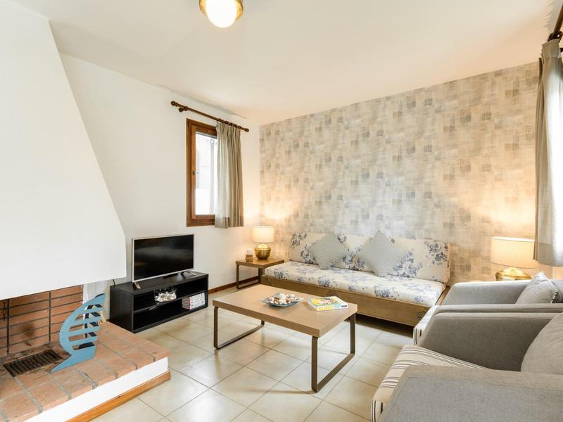 Soggiorno luminoso con divano, TV, tavolino e camino in un ambiente accogliente.