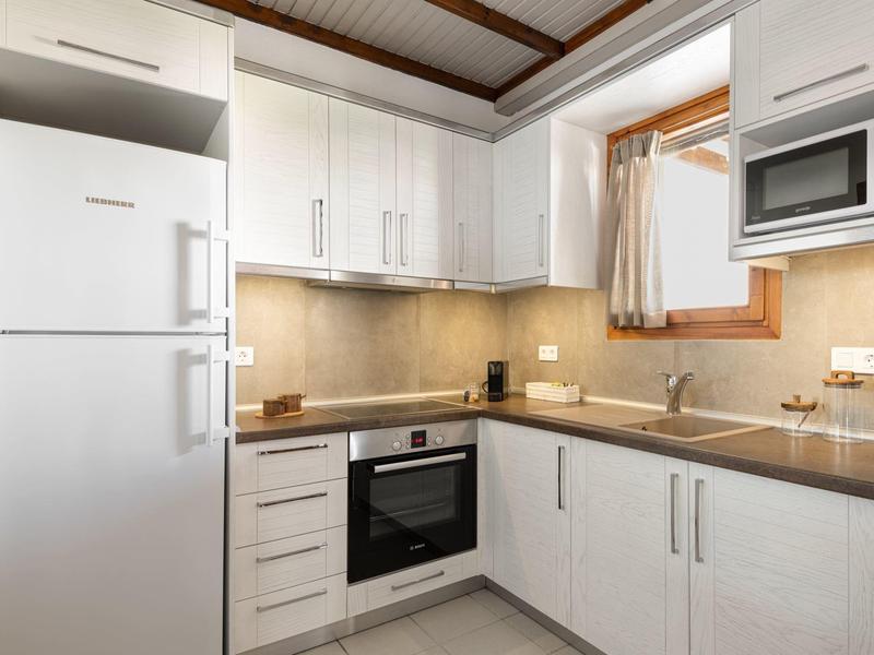 Cucina moderna con frigorifero, forno, microonde e armadietti bianchi.