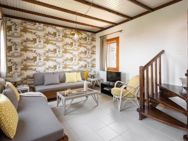 Soggiorno luminoso con divani grigi, tavolino, scala in legno, pareti bianche e carta da parati decorata.