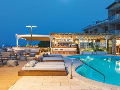 Oświetlony basen zewnętrzny i nowoczesne miejsca do wypoczynku w hotelu nocą.