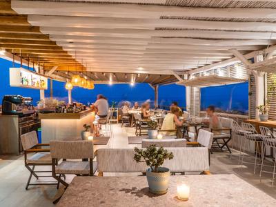 Przytulna otwarta jadalnia z drewnianymi belkami i widokiem na horyzont o zmierzchu.