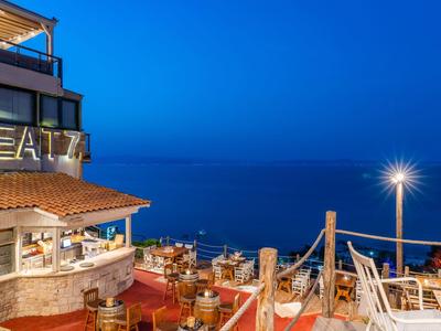 Zadaszony taras restauracyjny z widokiem na niebieskie morze nocą.