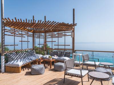 Nowoczesny zewnętrzny teren wypoczynkowy z pergolą i widokiem na morze pod czystym niebem