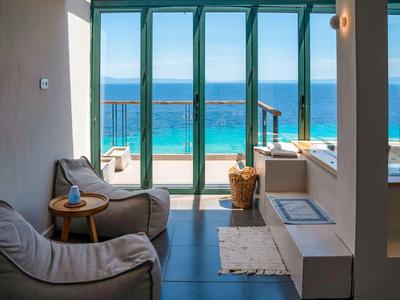 Nowoczesny pokój z wygodnymi fotelami i widokiem na morze przez duże szklane okna.