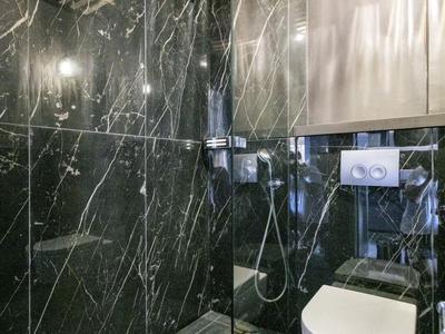 Modernes Hotelbadezimmer mit schwarzer Marmorwand, Regendusche und Wandtoilette.