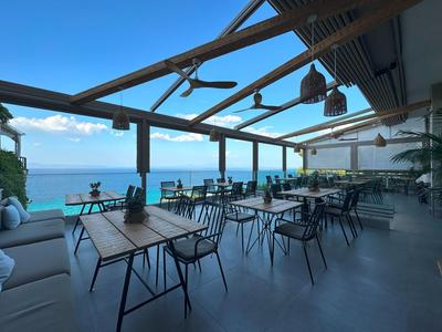 Offener Speisebereich eines Hotels mit Blick auf das Meer unter klarem Himmel.