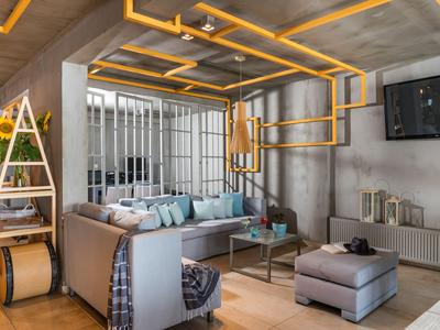 Modernes Wohnzimmer mit grauer Couch, TV und auffälliger gelber Deckenbeleuchtung.