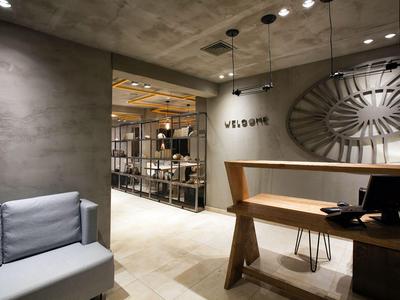 Moderner Hotel-Lobbybereich mit grauem Sofa, Holztresen und skulpturaler Wanddekoration.