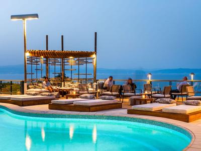Moderne Hotelpoolanlage mit Liegen und Meerblick bei Sonnenuntergang.