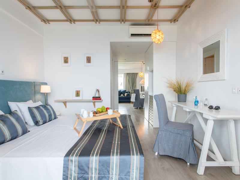 Nowoczesny pokój hotelowy z podwójnym łóżkiem, biurkiem, krzesłami i widokiem na sąsiedni pokój.