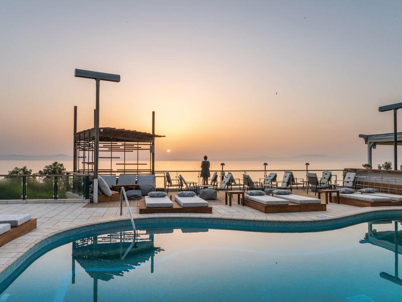 Strefa basenowa hotelu z leżakami o zachodzie słońca nad morzem