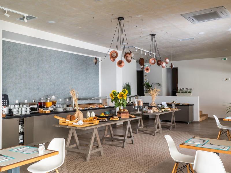 Nowoczesna sala śniadaniowa z bufetem, stołami i krzesłami, jasne i przyjazne wnętrze.