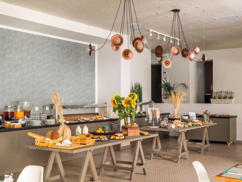 Bufet śniadaniowy z różnymi potrawami i napojami w nowoczesnym, jasnym pomieszczeniu.