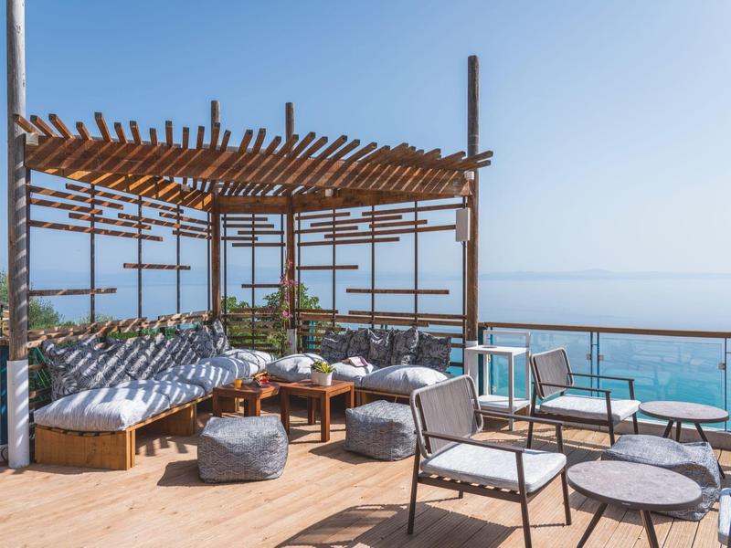 Nowoczesny zewnętrzny teren wypoczynkowy z pergolą i widokiem na morze pod czystym niebem