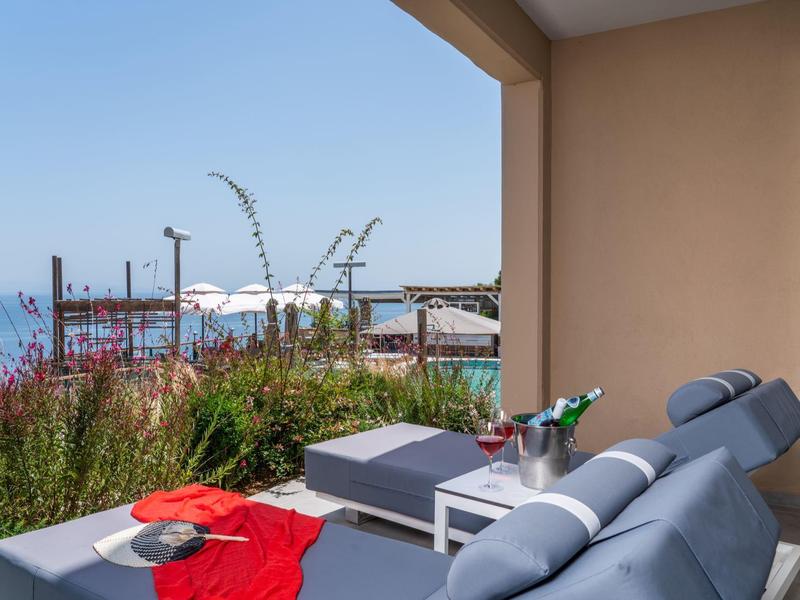 Balkon z szarymi meblami wypoczynkowymi i widokiem na morze przy czystym niebie.