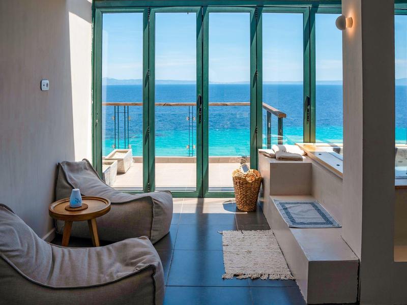 Nowoczesny pokój z wygodnymi fotelami i widokiem na morze przez duże szklane okna.
