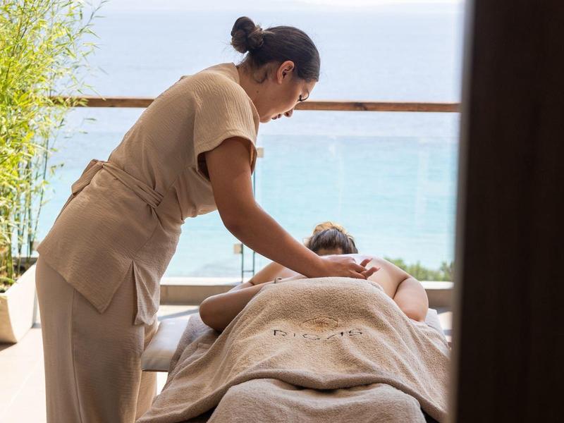 Kobieta otrzymująca masaż na tarasie z widokiem na morze w spa.