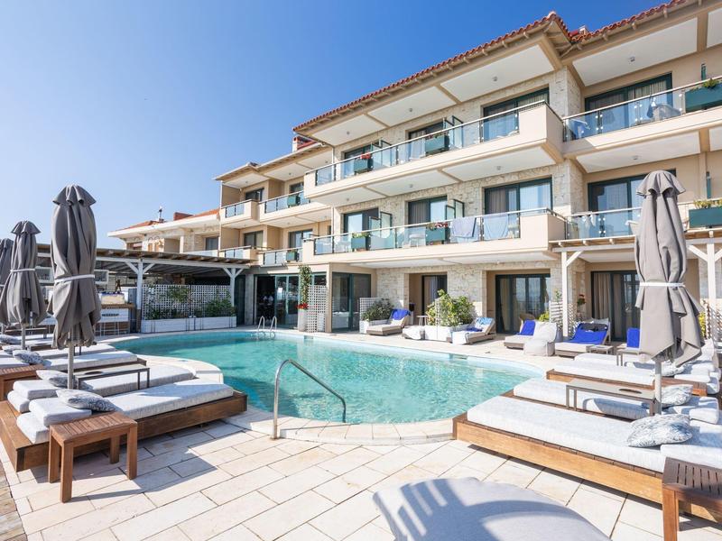 Nowoczesny basen z leżakami i parasolami przed budynkiem hotelu