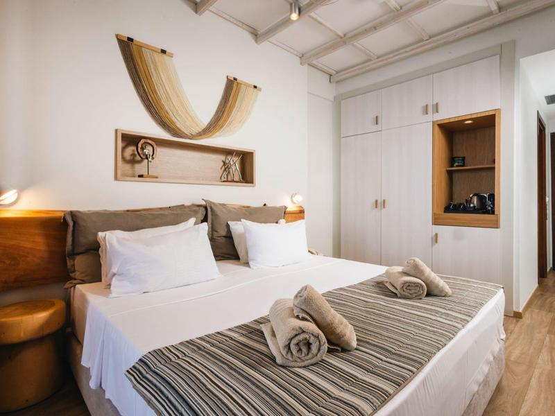 Nowoczesny pokój hotelowy z podwójnym łóżkiem, białymi ścianami i drewnianymi elementami.