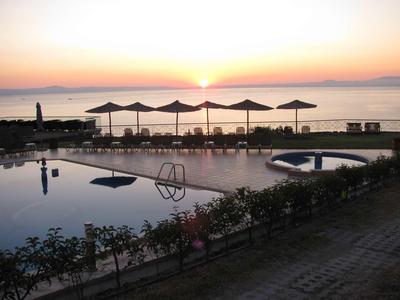 Piscina con ombrelloni al tramonto vicino al mare in un resort.
