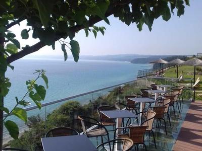 Espace extérieur avec tables et chaises donnant sur la mer et ciel clair.