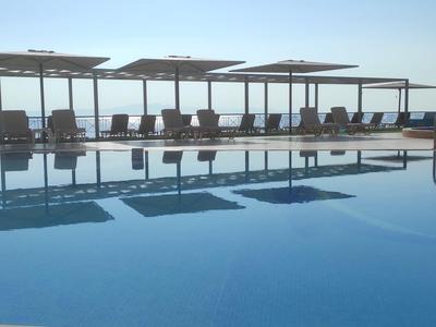 Ein ruhiger Pool mit Sonnenliegen und Sonnenschirmen am Strand bei klarem Himmel.