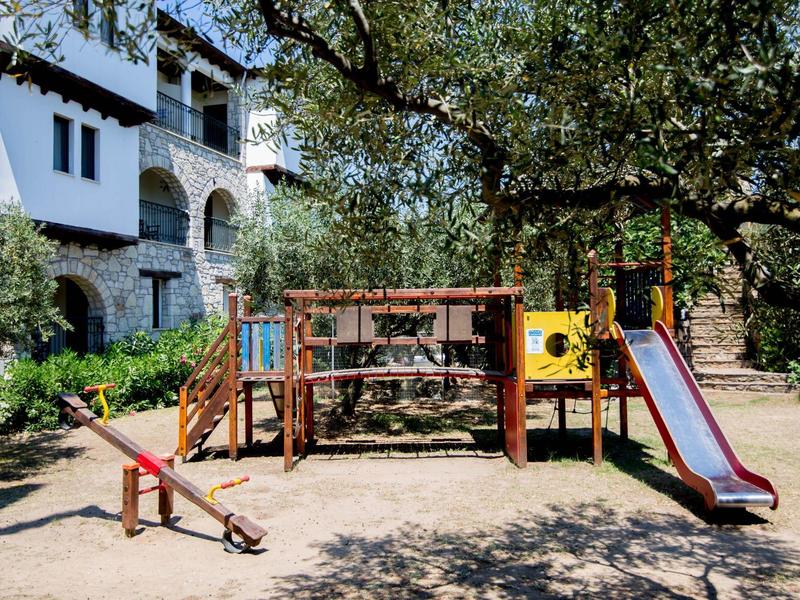 Kleurrijke restaurantstoelen en gedekte tafels onder gele zuilen en wijnranken.