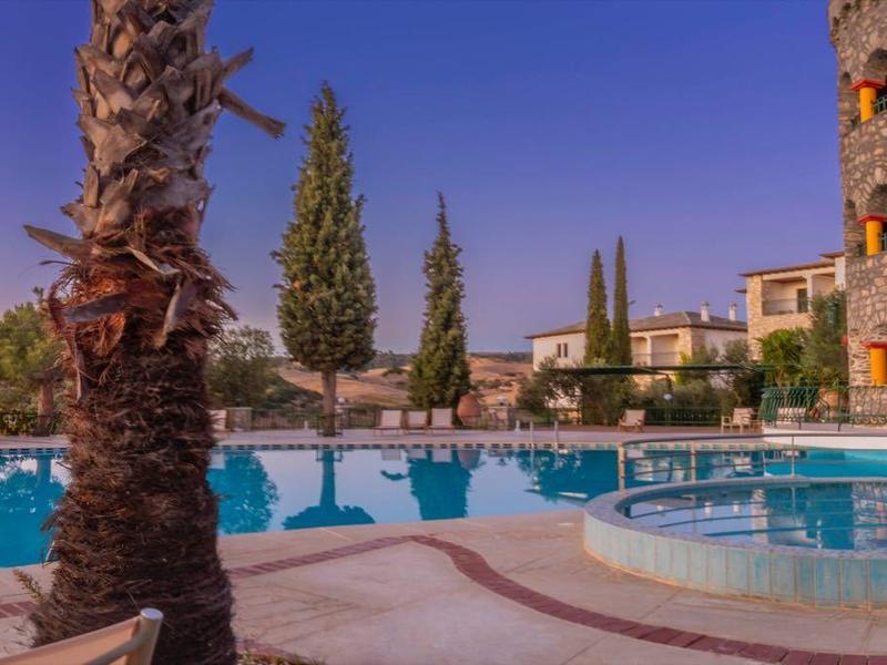 Luxe zwembadgebied met palmbomen en historische gebouwen bij zonsondergang.