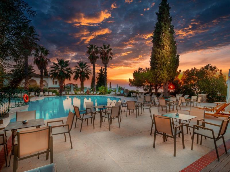 Buitenruimte van hotel met zwembad en tafels onder een dramatische avondlucht.