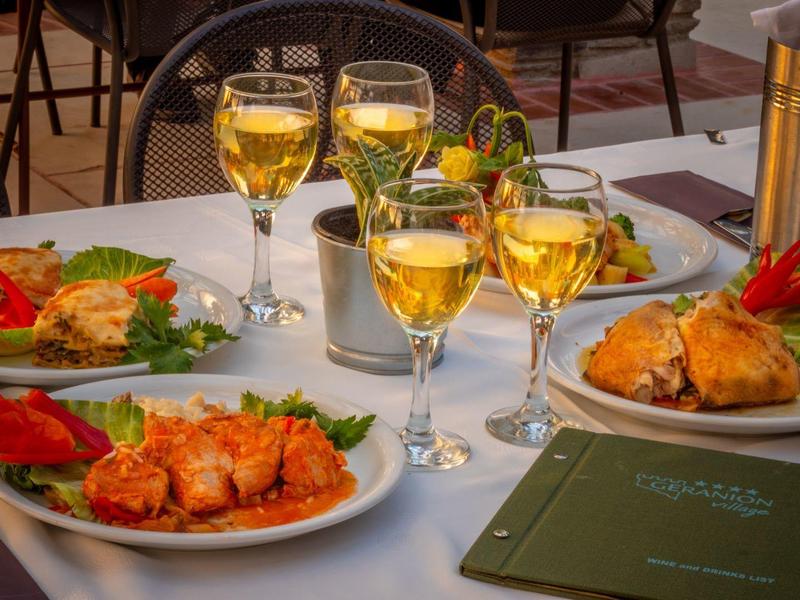 Verschillende borden met diverse gerechten en glazen witte wijn op een gedekte tafel.