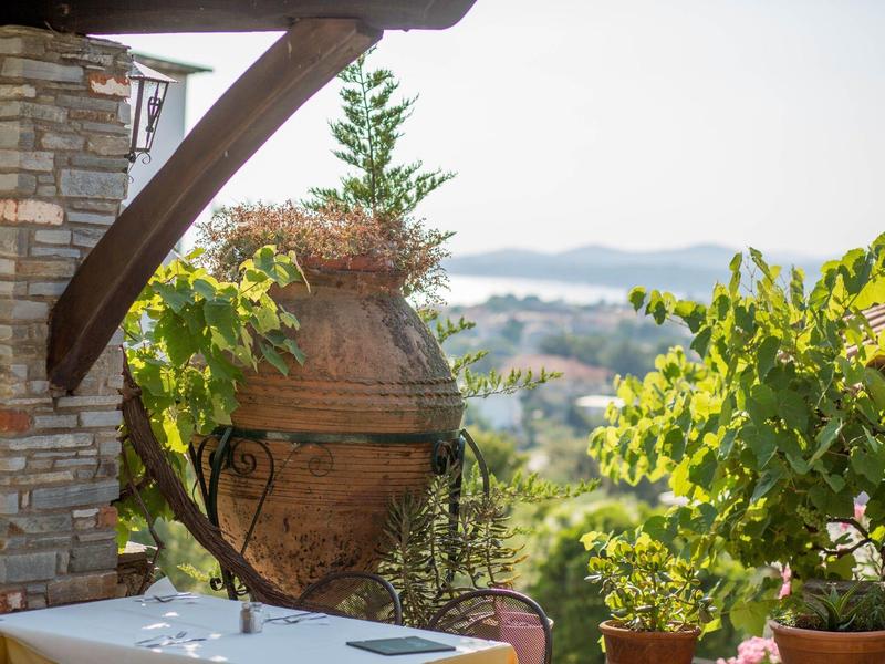 Terras met tafel, stoelen en grote plantenbakken met uitzicht op een bebost landschap.