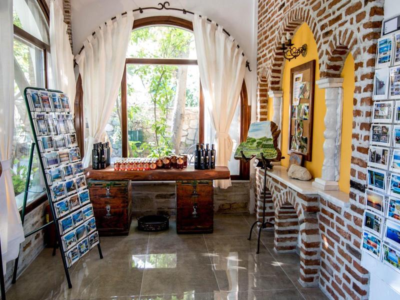 Lichte kamer met bruine bakstenen muren, grote ramen, bureau en ansichtkaartenrekken.