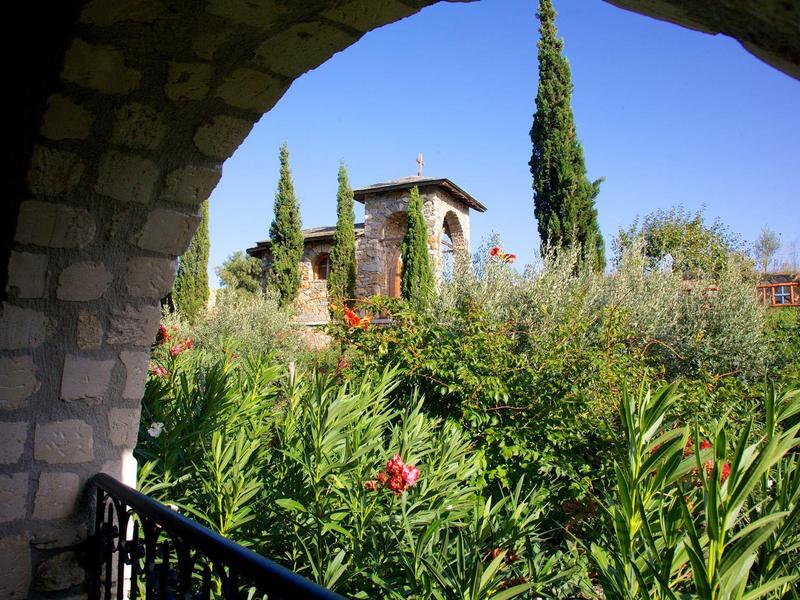 Uitzicht door een stenen boog op een tuin met hoge cipressen en mediterrane planten