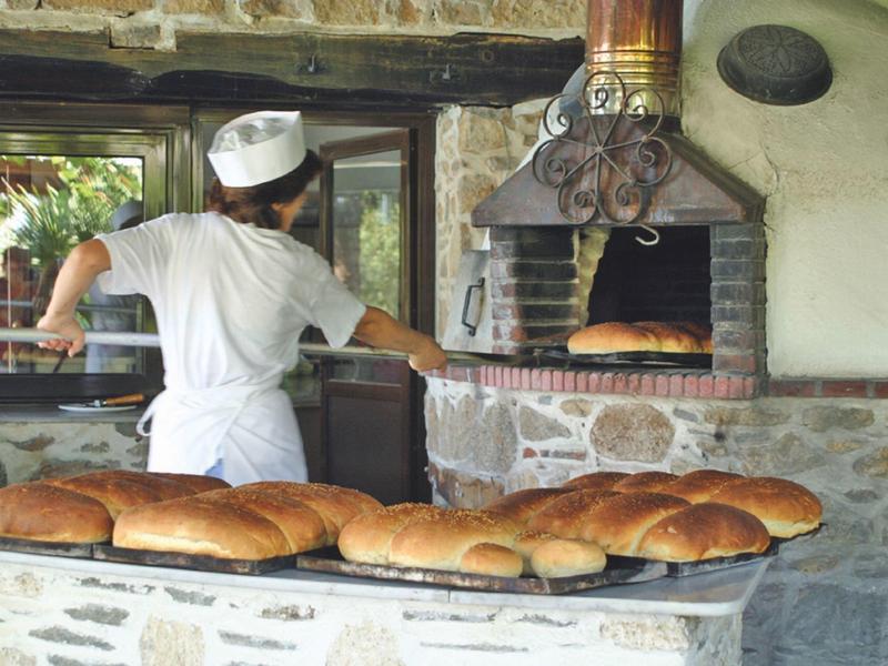 Bakker bakt brood in een traditionele houtoven in een rustieke bakkerij.