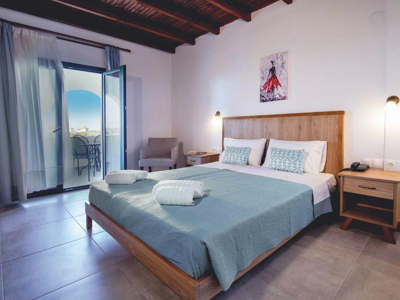 Lichte hotelkamer met houten bed, balkonuitzicht en minimalistische inrichting.