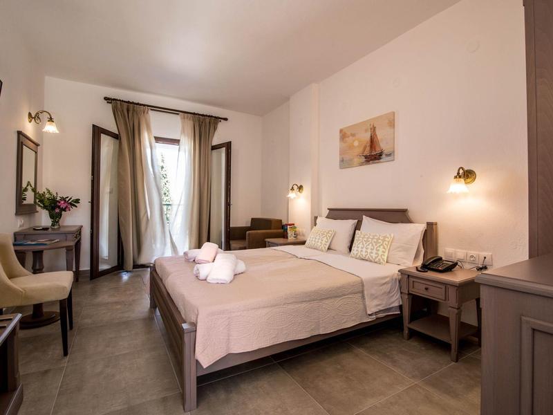 Lichte hotelkamer met tweepersoonsbed, nachtkastjes, stoel en bureau met tv.