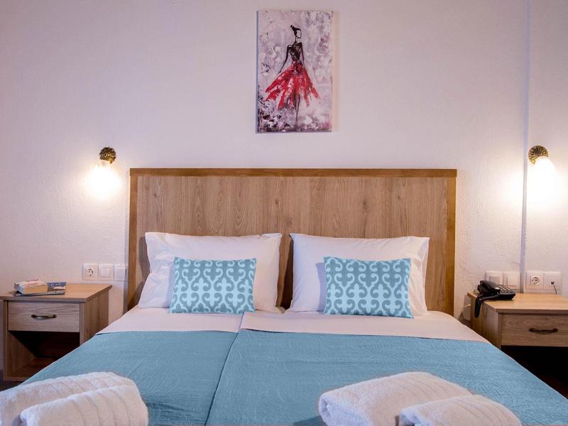 Gezellig tweepersoonsbed met blauwe dekens en twee nachtkastjes in een hotelkamer.