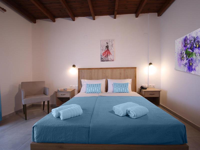 Moderne hotelkamer met blauw bed, twee handdoeken en eigentijdse wanddecoratie