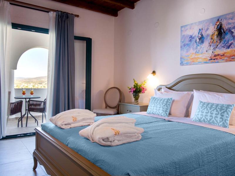 Gezellige hotelkamer met tweepersoonsbed en balkon met zithoek en zeezicht.