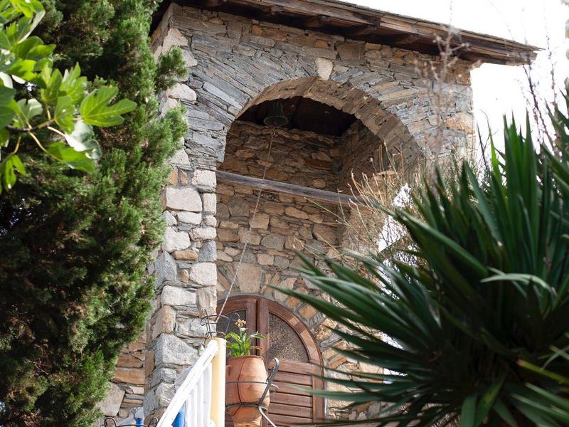 Steen trappen leiden naar een boog met een kruis, omgeven door weelderige vegetatie.