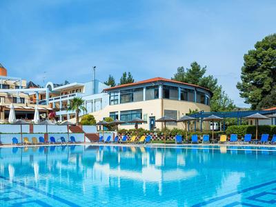 Klare Schwimmbadansicht mit Sonnenschirmen, Liegestühlen und Hotelgebäude im Hintergrund.