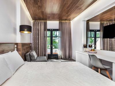 Habitación de hotel moderna con cama grande, techo de madera y ventana al balcón.