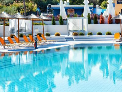 Piscina azul del hotel con tumbonas naranjas y sombrillas blancas al fondo.