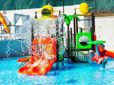 Parque acuático colorido con toboganes y fuentes en una piscina de hotel.