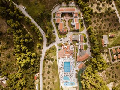 Vista aérea de un hotel con piscina, rodeado de árboles y caminos rurales.
