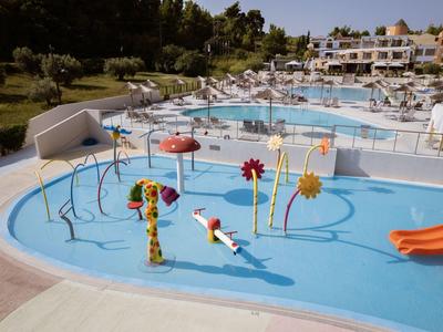 Parque acuático colorido con figuras y toboganes junto a una piscina de hotel y tumbonas.